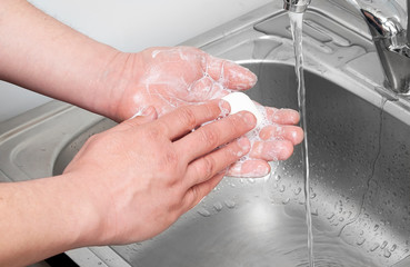 Closeup of a hand with soap under a stream of water. Wash from dirt. Foam thoroughly wash off your...