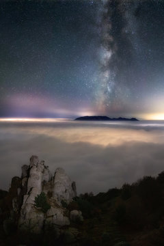 Night Landscape with rocks above the clouds under the stars and the Milky Way