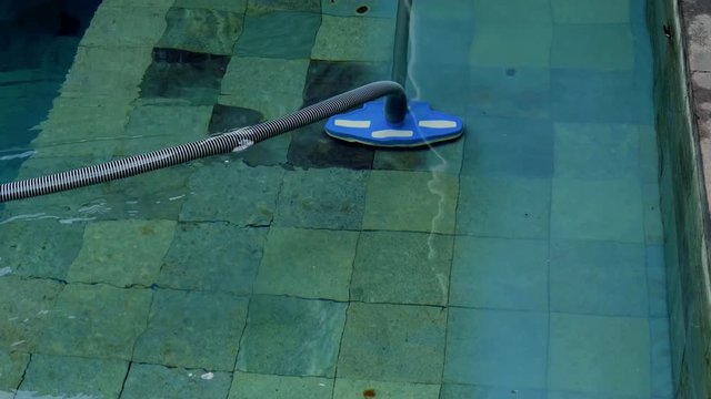 Man cleaning swimming pool with manual underwater vacuum cleaner. Service and technology.