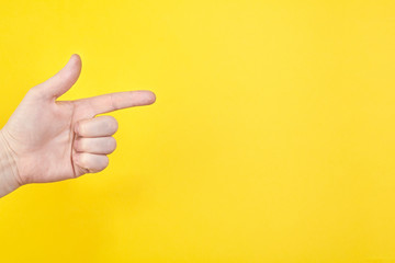 Hand show gesture on an isolated yellow background in studio