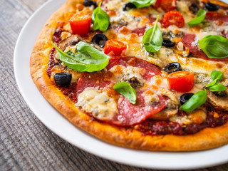 Pizza with pepperoni gorgonzola and champignons on wooden table
