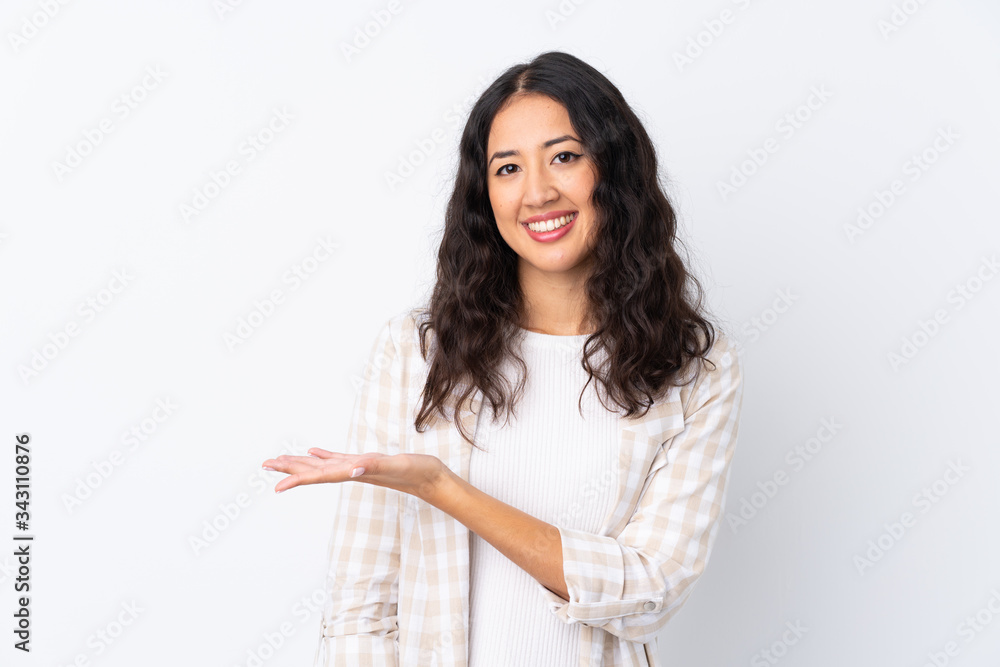 Wall mural mixed race woman over isolated white background presenting an idea while looking smiling towards