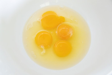 4 eggs cracked open with the yolk and the egg white inside with 3 whole yolks and one broken one