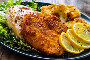 Pork chops with fried cauliflower and vegetable salad on wooden background