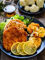 Pork chops with fried cauliflower and vegetable salad on wooden background