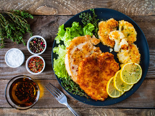 Pork chops with fried cauliflower and vegetable salad on wooden background