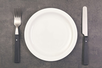 food concept - top view plate with knife, spoon on gray concrete