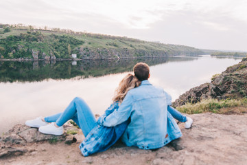 Naklejka na ściany i meble couple in love in blue jeans and white shirts in nature, where the field and rocks