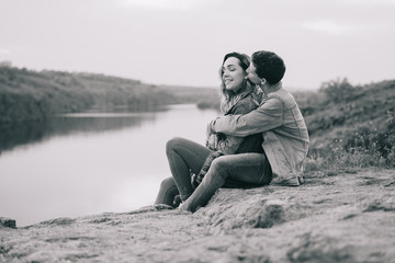 couple in love in blue jeans and white shirts in nature, where the field and rocks