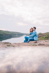 couple in love in blue jeans and white shirts in nature, where the field and rocks