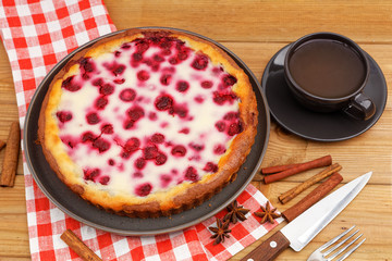 Homemade raspberry pie with yogurt filling and cup of tea on wooden table. Angle view.