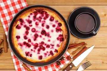 Homemade raspberry pie with yogurt filling and cup of tea on wooden table. Top view.