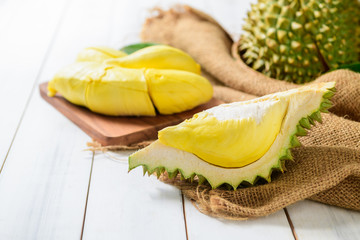 Fresh cut durian (monthong) on sack and white wood background,