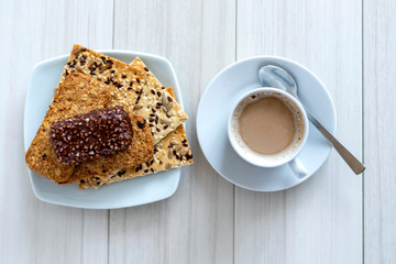 Cup of coffee with cereal cookies on a white wooden table. Breakfast time.