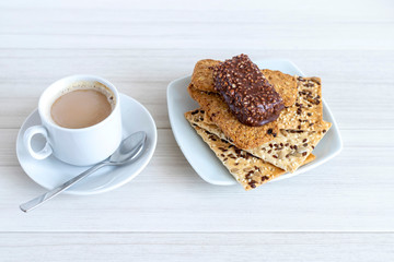 Cup of coffee with cereal cookies on a white wooden table. Breakfast time.