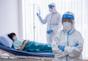 Two asian doctor wear PPE suit with N95 mask and face shield, treat and use oxygen mask with coronavirus infected patient in negative pressure room. Coronavirus, medical and covid19 concept.