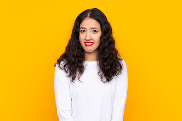 Mixed race woman over isolated yellow background having doubts and with confuse face expression