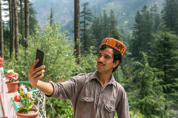 man with traditional himachali cap and taking selfie with smart phone