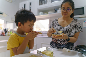 Asian eating butter bread with his mother