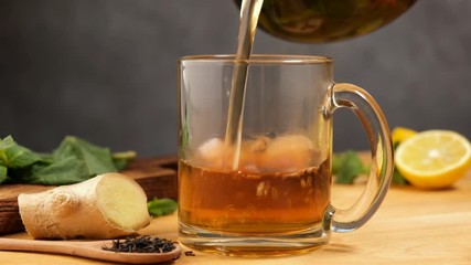 Pouring lemon ginger tea in glass cup. Healthy herbal hot drink - Powered by Adobe