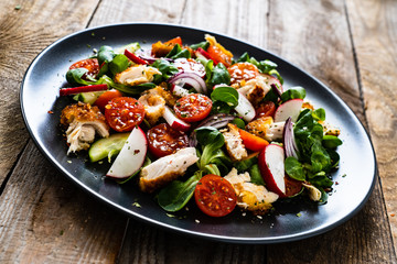 Caesar salad - fried chicken breast and vegetables on wooden table
