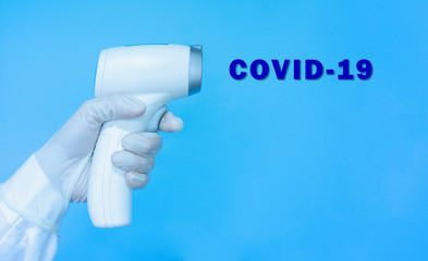 Woman doctor wearing gloves, holding medical infrared forehead thermometer or thermometer gun for checking and screening body temperature with text Covid-19. Coronavirus, covid-19 and medical concept.