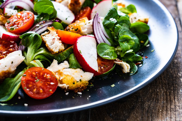 Caesar salad - fried chicken breast and vegetables on wooden table
