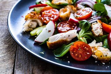 Caesar salad - fried chicken breast and vegetables on wooden table
