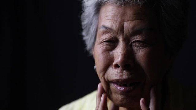 Portrait of an elderly Chinese woman with dark background. 