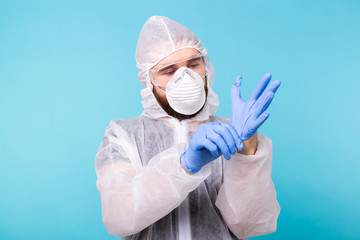 Professional for disinfection efforts. Epidemiologist man puts on protective suit and gloves. Coronavirus, covid-19 and pandemic concept.