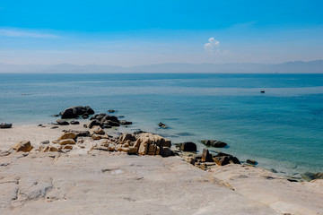 Beautiful seascape with blue sea, rocks, sand, and bright blue sky at a small island in Binh Thuan province, Vietnam. Royalty high-quality free stock image of the sea landscape.