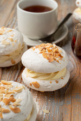 Meringue stuffed with whipped cream custard and almond flakes, served with a cup of tea on vintage-style table