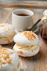 Meringue stuffed with whipped cream custard and almond flakes, served with a cup of tea on vintage-style table