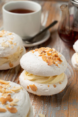 Meringue stuffed with whipped cream custard and almond flakes, served with a cup of tea on vintage-style table