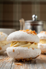Meringue stuffed with whipped cream custard and almond flakes, served with a cup of tea on vintage-style table