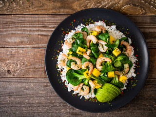 Prawns with rice and vegetables on wooden table
