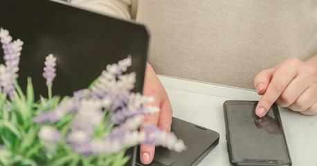 Obraz premium confident businesswoman types on black smartphone and modern notebook at plant closeup