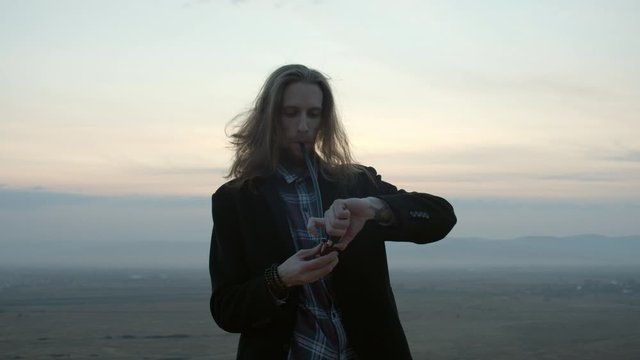 long haired guy smoking pipe in the sunset