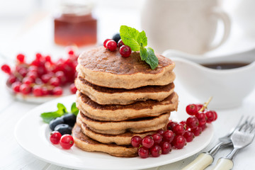 Stack of whole wheat pancakes with berries on white table. Tasty sweet breakfast food