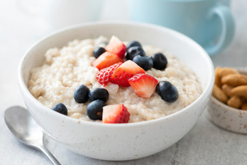 Breakfast oatmeal porridge with strawberry, blueberry in white bowl, Closeup view of healthy breakfast meal