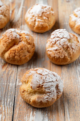 Close up of golden crust profiterole stuffed with buttercream on vintage wooden table