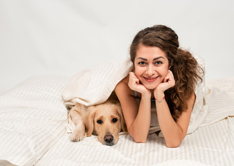Happy Female woman sleep in pajamas lying in bed with her golden retriever dog. Romantic relationship human and dog concept