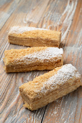 Mille-feuille with custard and puff dough, traditional russian treat, cut and served on wooden vintage table