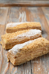 Mille-feuille with custard and puff dough, traditional russian treat, cut and served on wooden vintage table