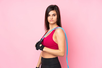 Young sport woman over isolated pink background with jumping rope