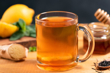 Ginger lemon tea in glass cup on wooden table, closeup view. Hot ginger tea