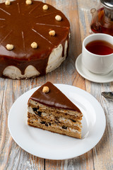 A mouthwatering slice of hazelnut meadow torte with caramel and a cup of black tea
