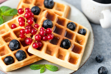 Square belgian waffles with summer berries on plate, tasty sweet breakfast food
