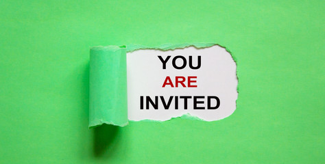 The text 'you are invited' appearing behind torn green paper.
