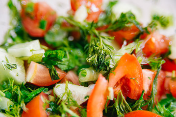 Spring or summer salad with fresh vegetables, tomatoes and cucumber in a bowl on a white background. Healthy raw food and vegetarian concept